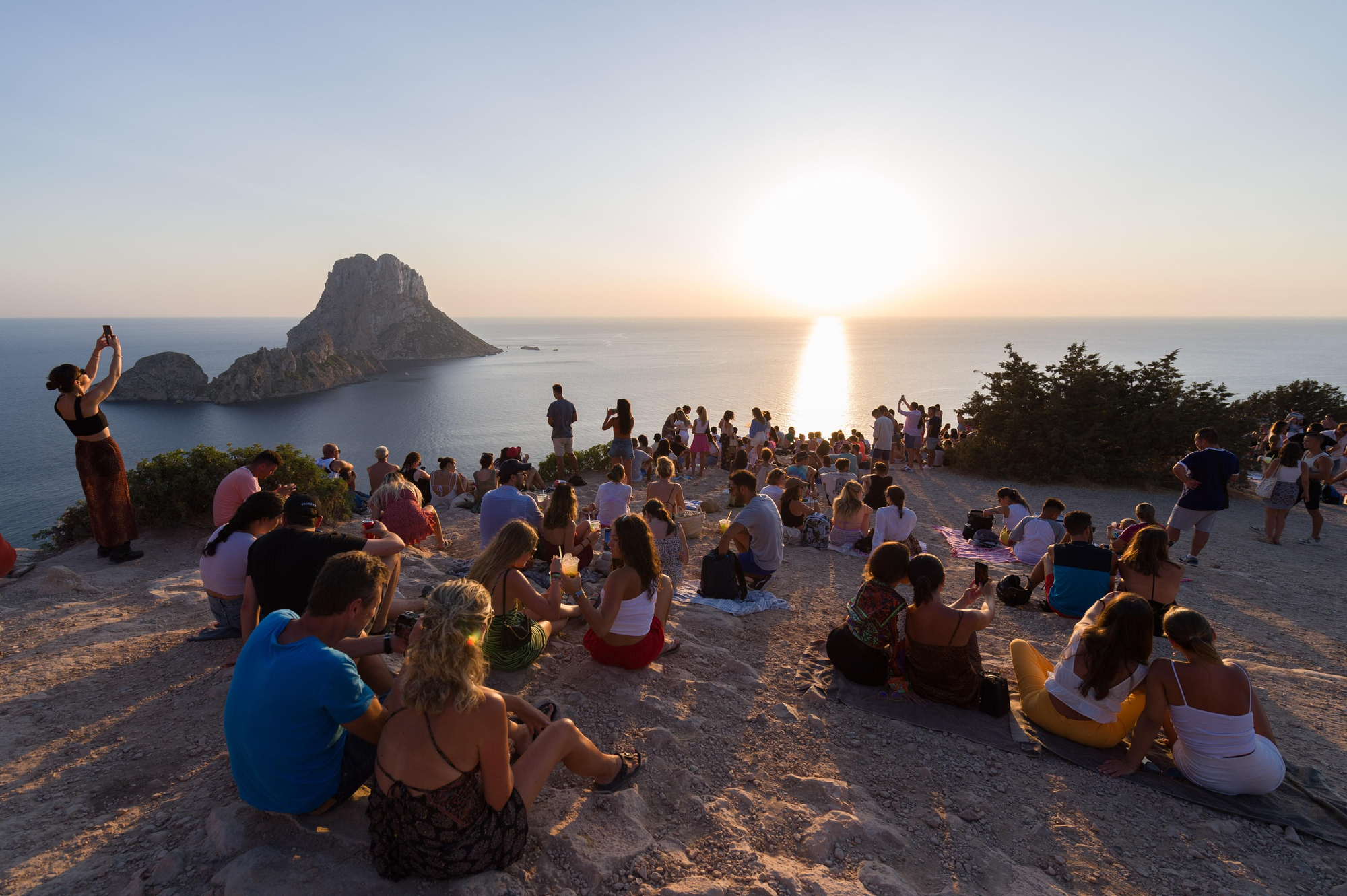 Decenas de turistas disfrutan de la puesta de sol de Cala d’Hort en s’Era des Mataret, uno de los lugares con mayor reclamo