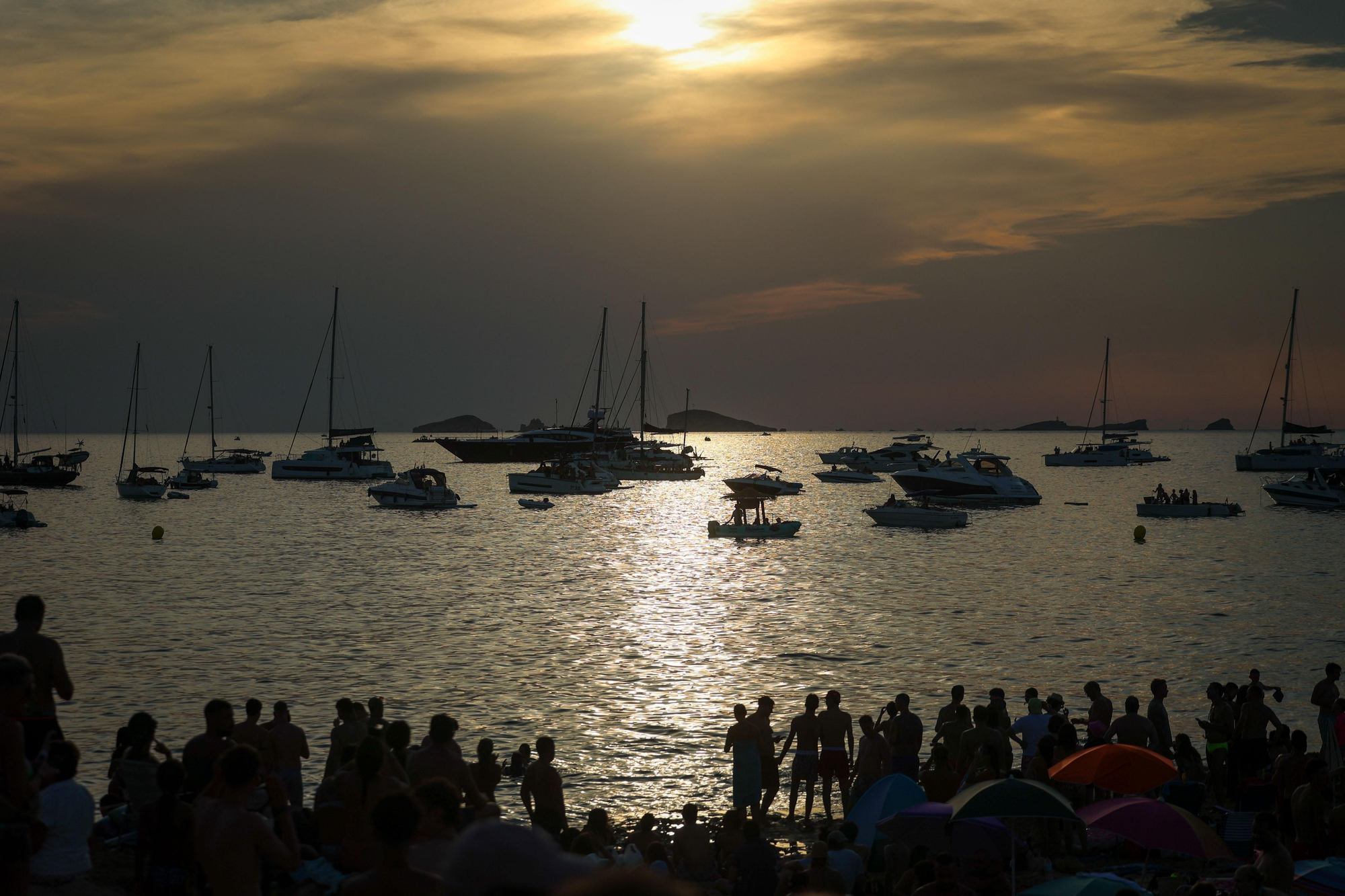 La luz del atardecer comienza a volverse difusa sobre las decenas de embarcaciones fondeadas en la costa de Sant Josep, minutos antes de que la Luna comience a devorar el disco solar