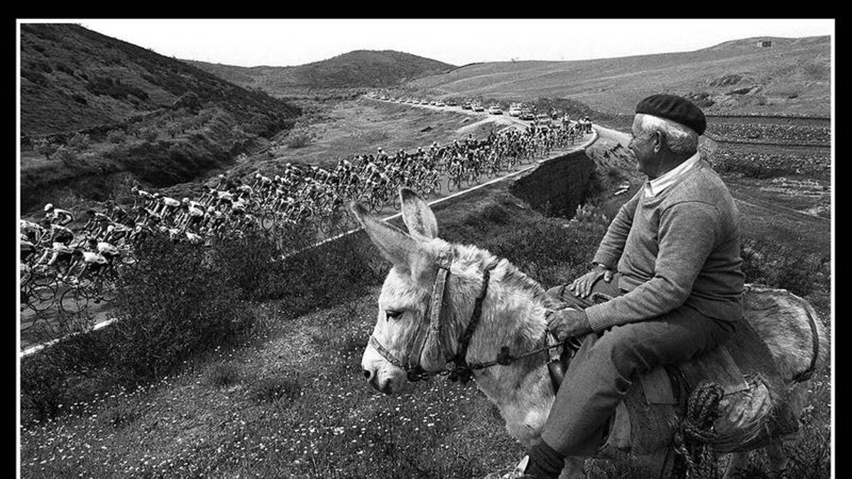 Un hombre montado sobre un burro al paso de la Vuelta Ciclista a España de 1990.