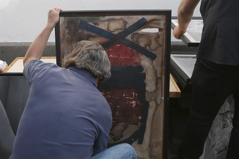Un socio del Ateneo de La Laguna intenta proteger la tela de un cuadro que se ha roto en el incendio desatado esta tarde en el interior del edificio, cuyo tejado se ha derrumbado completamente. EFE/ Cristóbal García