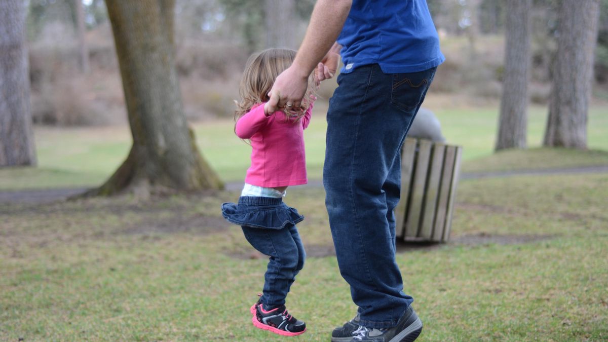 Una niña saltando con su padre.