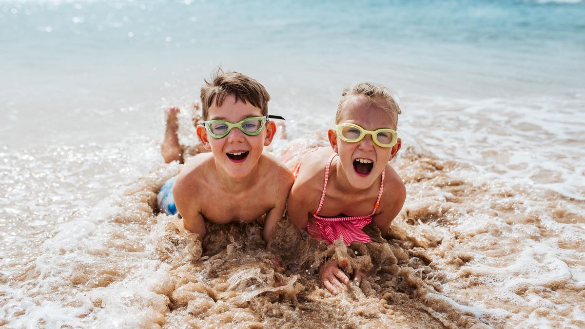 Dos nens gaudeixen d'un bany a la platja