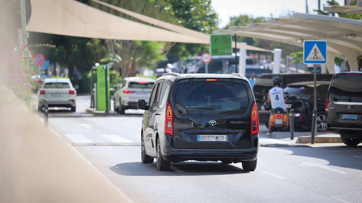 Un furgó Toyota de color negre i amb matrícula blanca circula per la carretera davant de l'aeroport