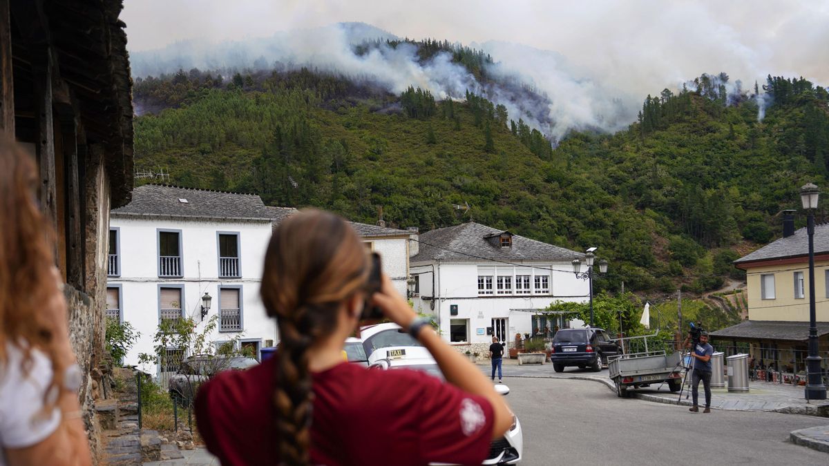 Dos mujeres captan con sus móviles las imágenes del incendio en San Antolín de Ibias, este miércoles.
