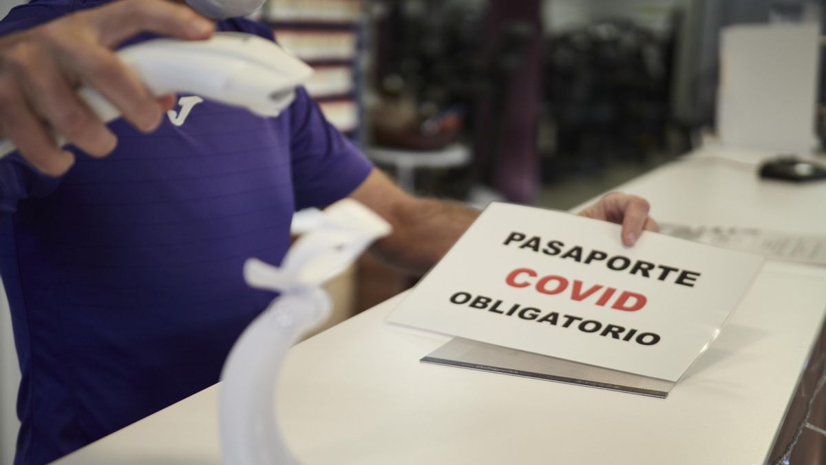 Archivo - Un trabajador escanea el pasaporte Covid a una usuaria.