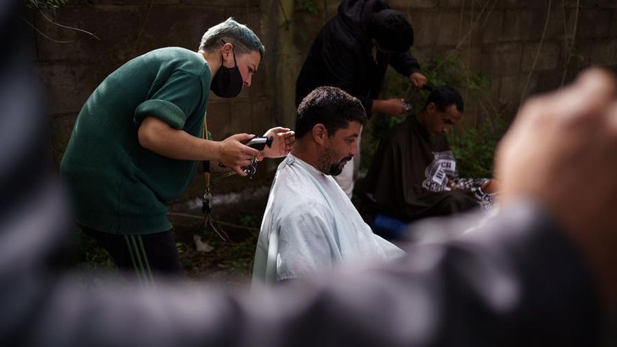 Patri, una peluquera voluntaria, corta el pelo a uno de los inmigrantes en el exterior del campamento