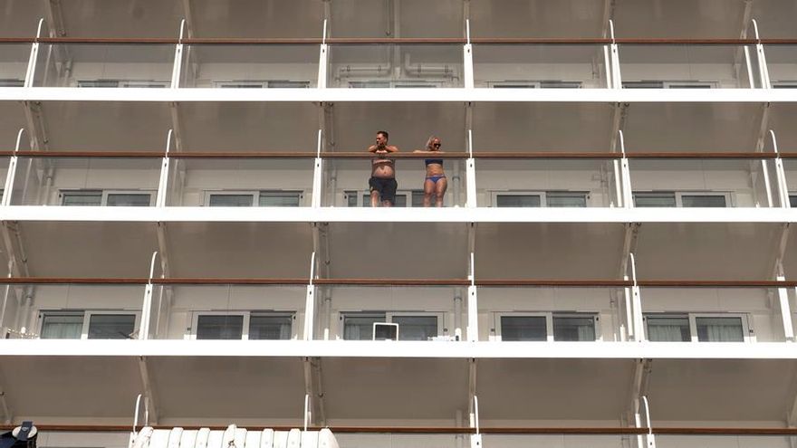 Dos cruceristas observan Santa Cruz de Tenerife desde su camarote en el buque Mein Shiff 2 a su llegada al puerto.