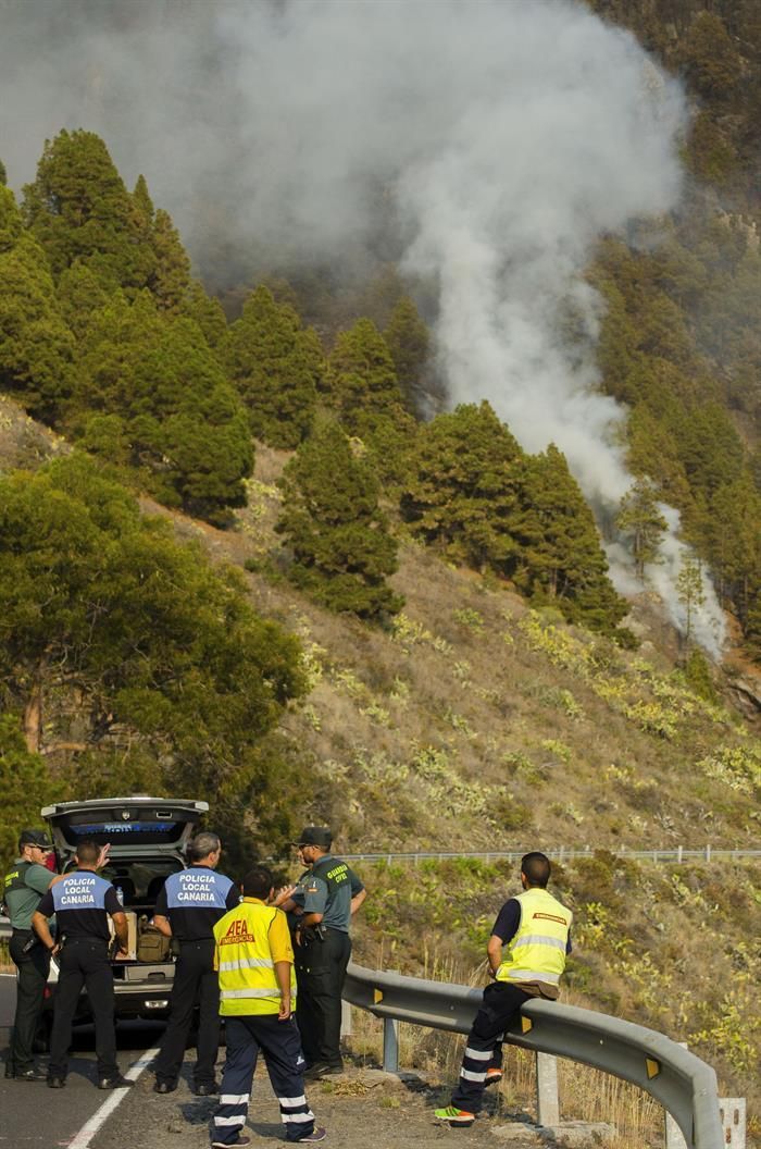 Un grupo de agentes en la posición de control de acceso a la carretera general ante la inminente llegada de las llamas del fuego en el municipio de El Paso