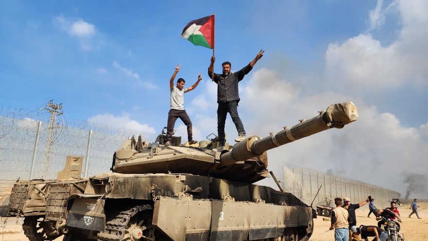 Palestinos celebran el avance de Hamás sobre un vehículo militar israelí en la ciudad de Gaza, el 7 de octubre de 2023.
