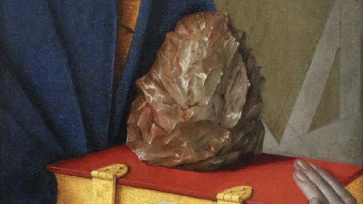 El santo aparece con un libro cerrado sobre el que descansa una piedra que resulta coincidir con la forma de un hacha achelense