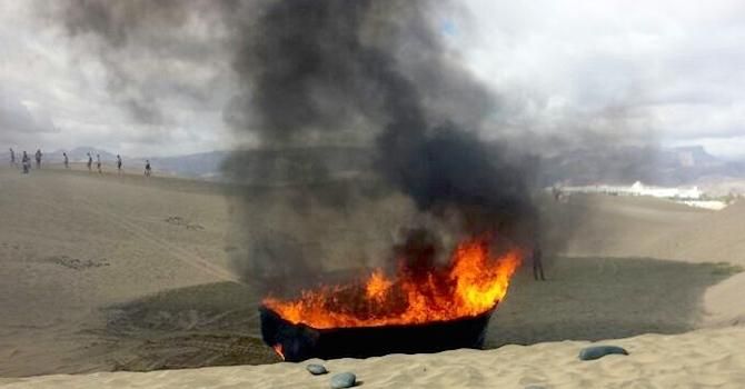 Patera en la que llegaron los inmigrantes este miércoles a Playa del Inglés siendo incinerada en la misma playa.