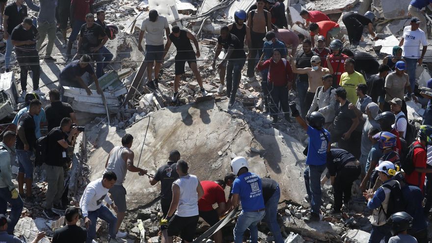 Personas junto a los escombros de un edificio colapsado por el terremoto este lunes en Cali (Colombia).