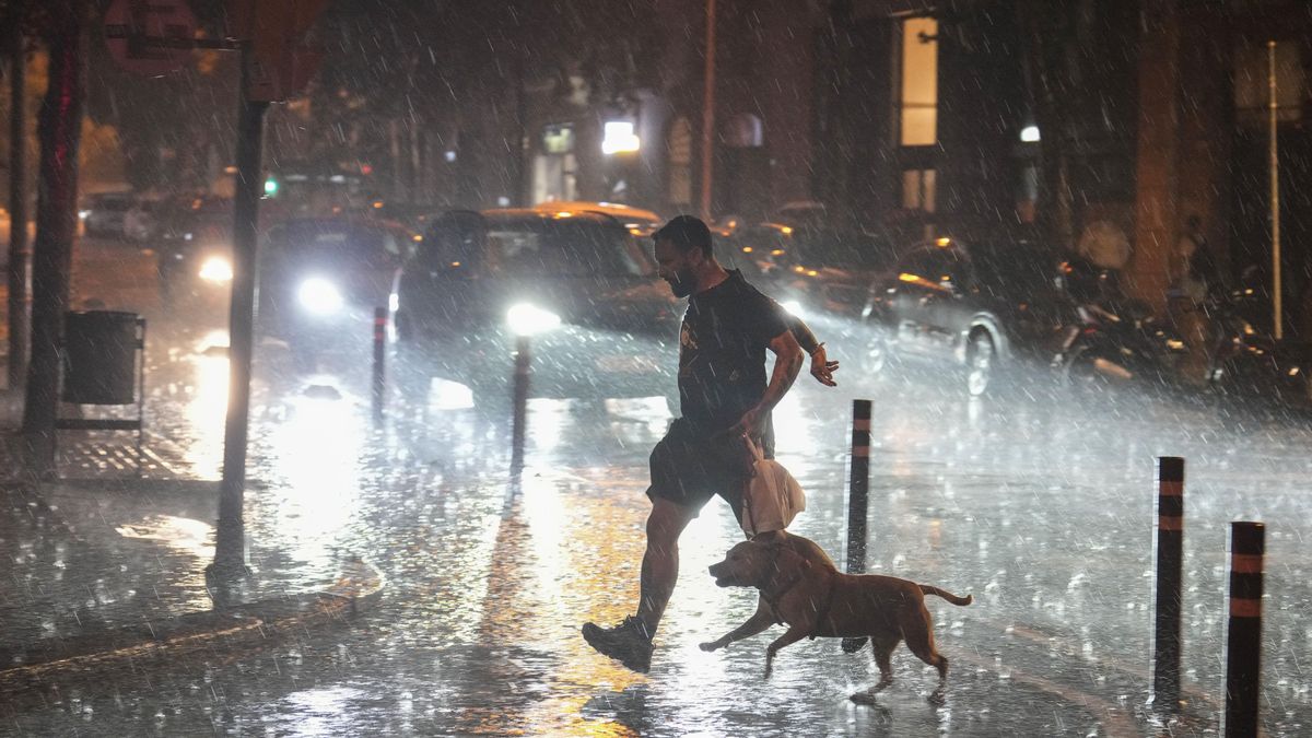 Un hombre intentando protegerse de la lluvia en Catalunya