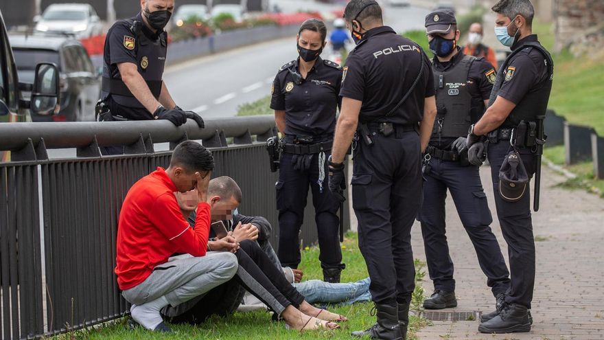 Varios agentes de la Policía Nacional hablan con un grupo de inmigrantes en las calles de Ceuta este viernes. EFE/Brais Lorenzo