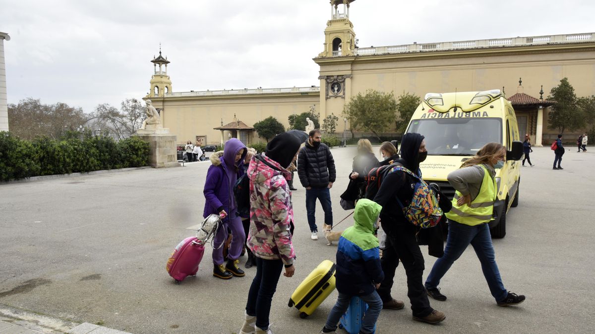 Varios refugiados y una traductora junto a una ambulancia