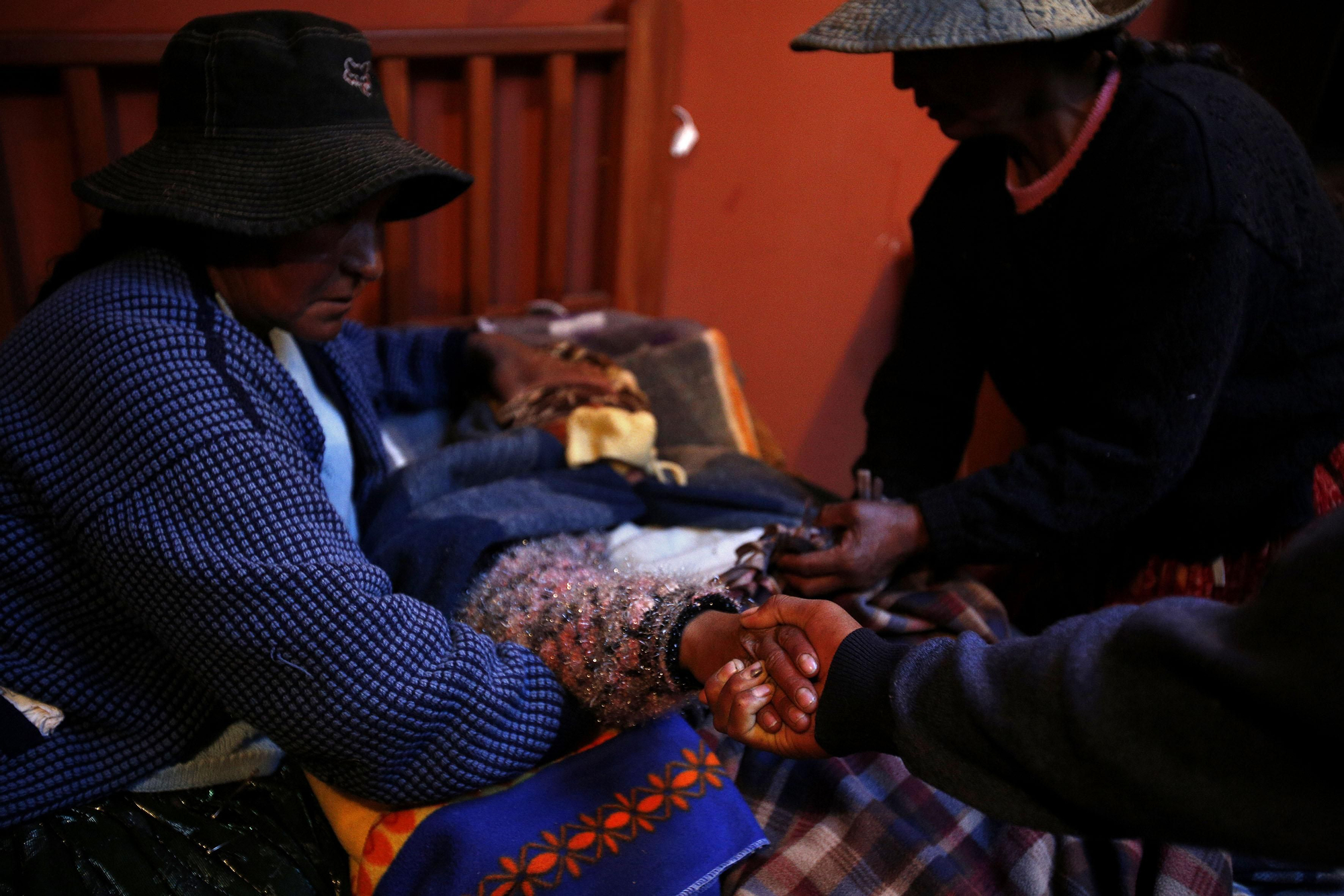 Miguel agarra la mano a su esposa Janet mientras ella sufre los dolores de una contracción apoyada por su suegra Juana y otra familiar poco antes de dar a luz en una sala intercultural acondicionada por Médicos del Mundo en el Hospital de Patacamaya / Fotografía: Olmo Calvo