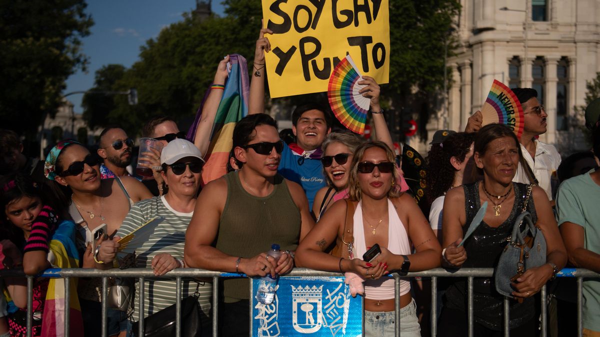 Un joven sonríe mientras levanta una pancarta que reza "soy gay y punto"