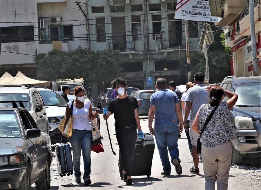 La gente camina con sus pertenencias después de ser evacuados de sus viviendas dañadas.