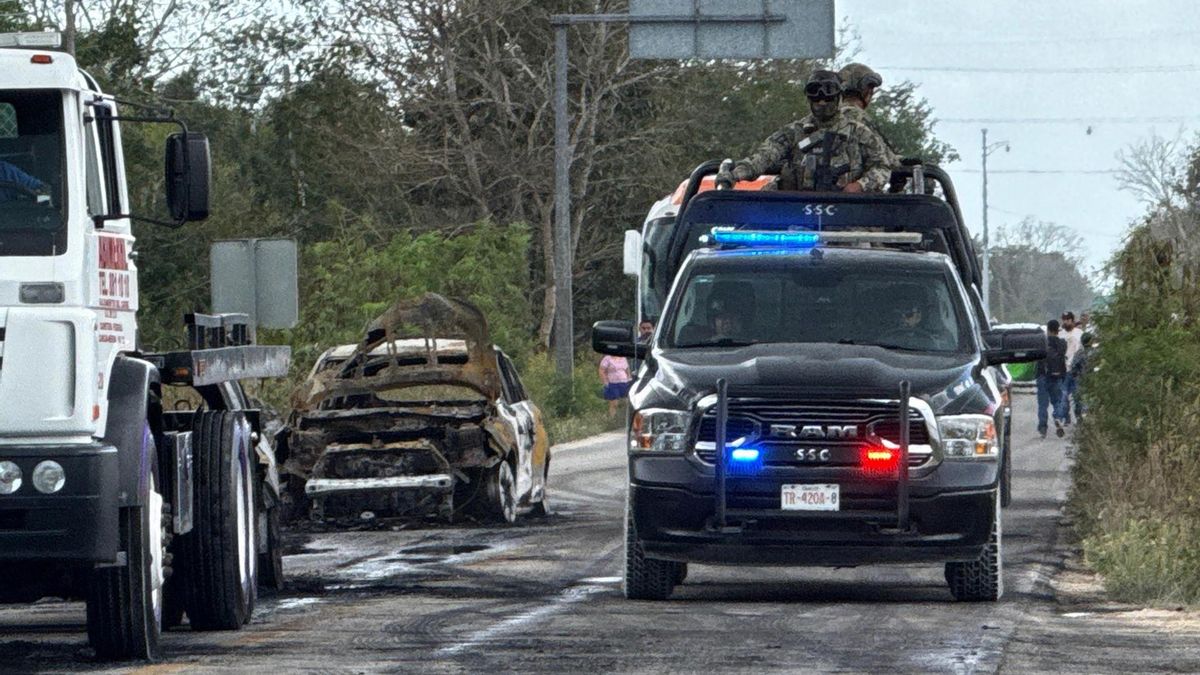 Integrantes de la Policía custodian la zona donde fue incendiado un vehículo por integrantes del crimen organizado, en el balneario de Cancún en Quintana Roo.
