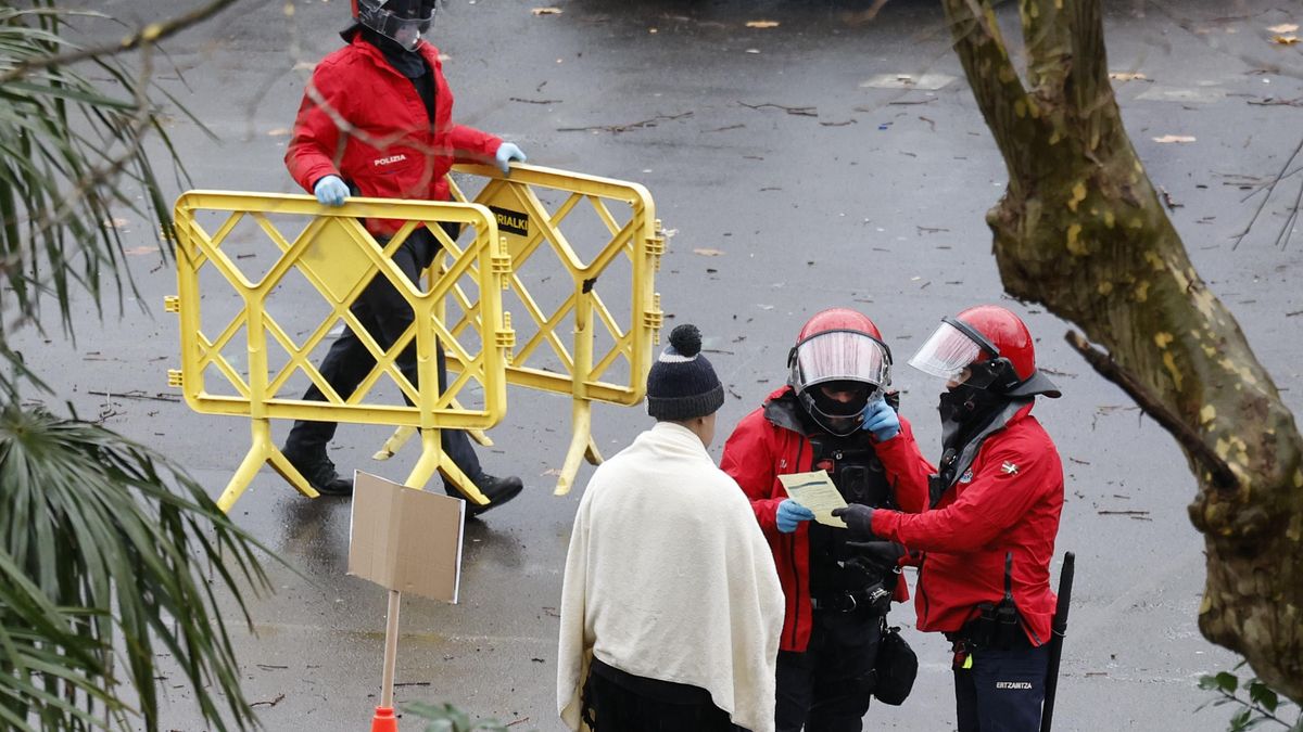 Agentes de la Ertzaintza con una de las personas desalojadas este jueves de la antigua escuela de Martutene, en Donostia