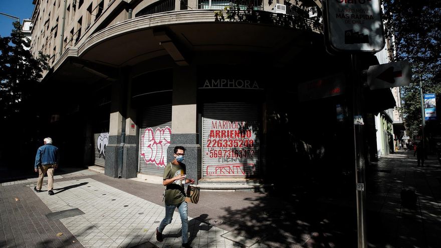 Personas caminan por una calle vacía, durante una cuarentena, por el centro de Santiago (Chile).