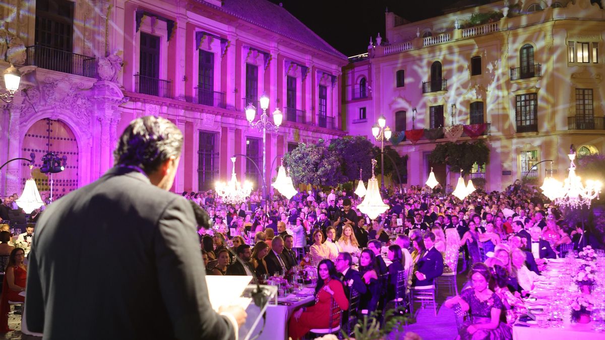 El promotor habla a sus invitados con el palacio arzobispal a su izquierda.