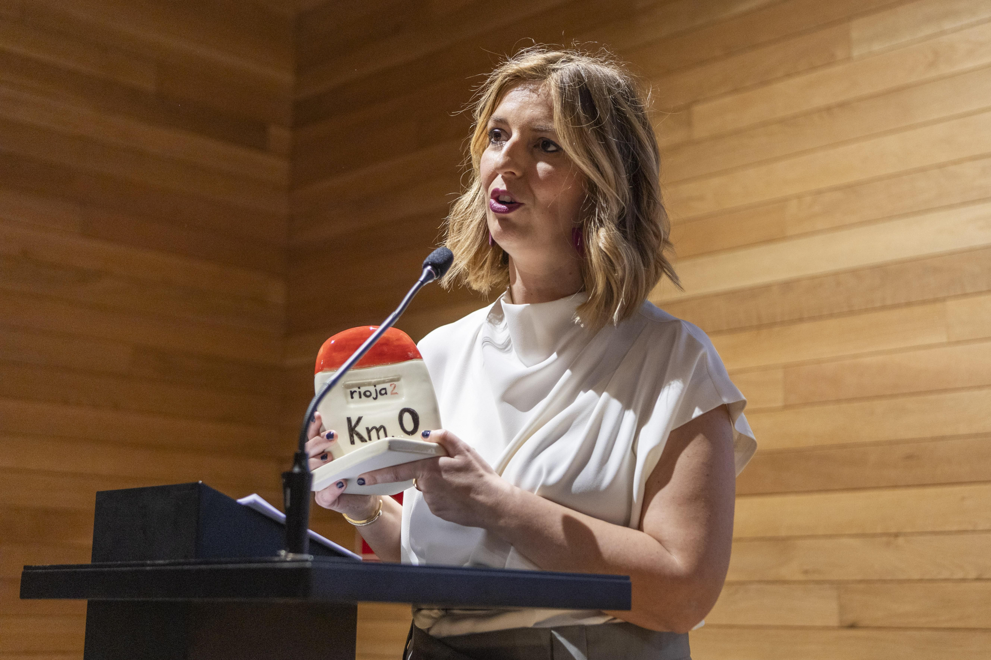 Olivia García muestra el premio, un punto kilométrico hecho de forma artesana por el alfarero Antonio Naharro