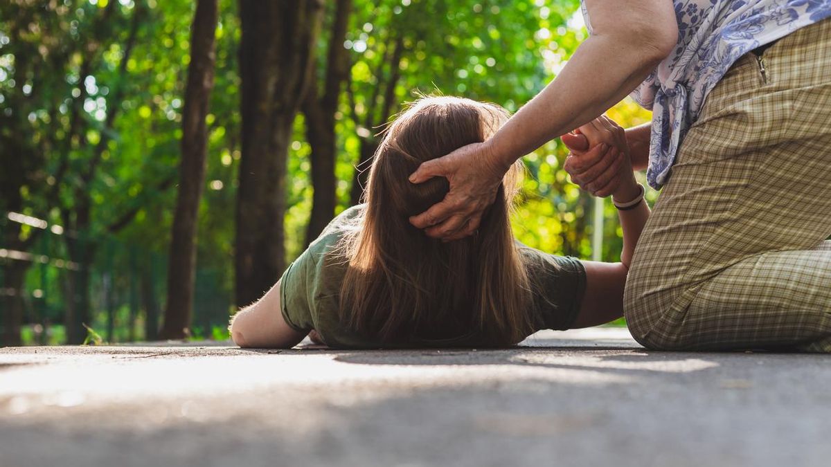 Una mujer ayuda a una joven con una crisis de epilepsia.