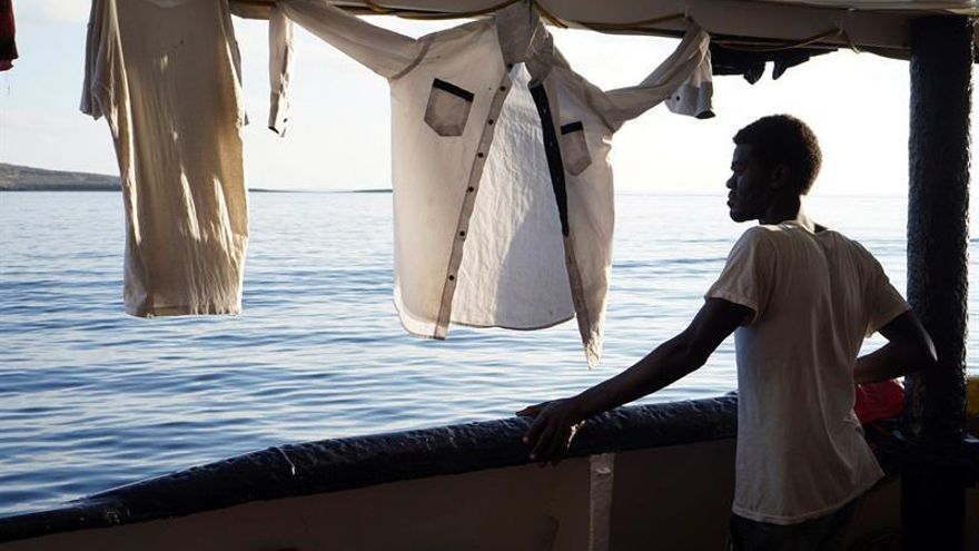 Un migrante mira este domingo desde la cubierta de el buque "Open Arms" las costas de Lampedusa (Italia). Siguen a bordo 107 personas rescatadas hace 16 días en el Mediterráneo en condiciones muy difíciles.