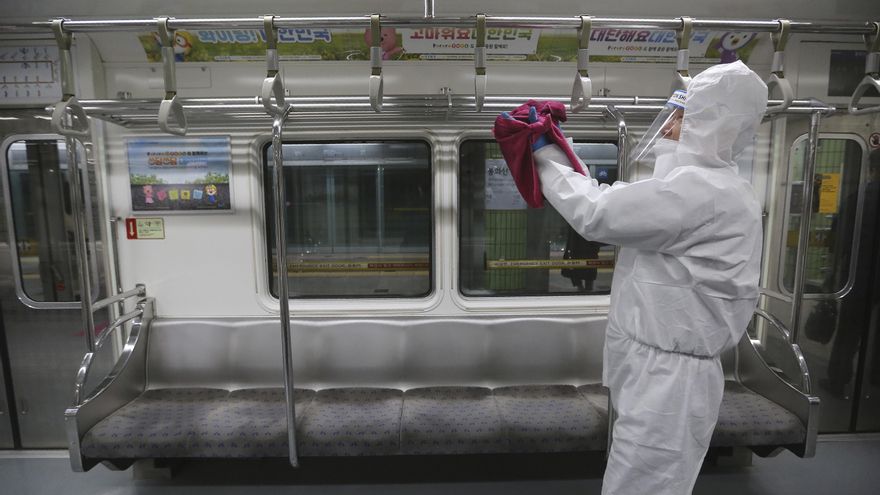 Un empleado desinfecta asas como precaución contra el coronavirus en un tren de metro en una estación de metro en Seúl, Corea del Sur