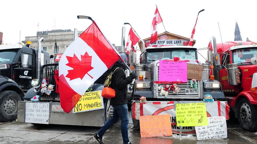 Una persona lleva la bandera canadiense mientras los camioneros continúan protestando por los mandatos de vacunación en el centro de Ottawa.