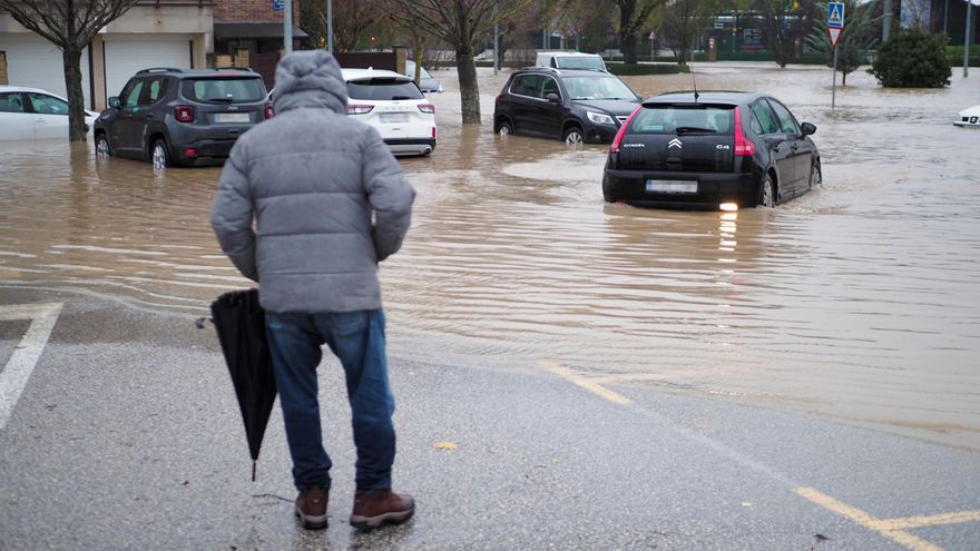 Una persona al lado de una vía llena de coches rodeados de agua.