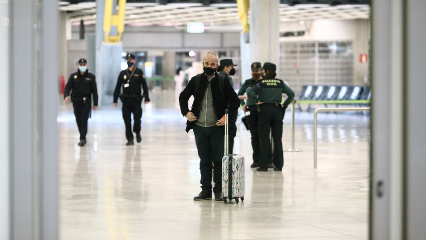 Un pasajero con maleta junto a agentes de la Guardia Civil en la terminal T4 del Aeropuerto de Madrid-Barajas Adolfo Suárez, en Madrid (España),