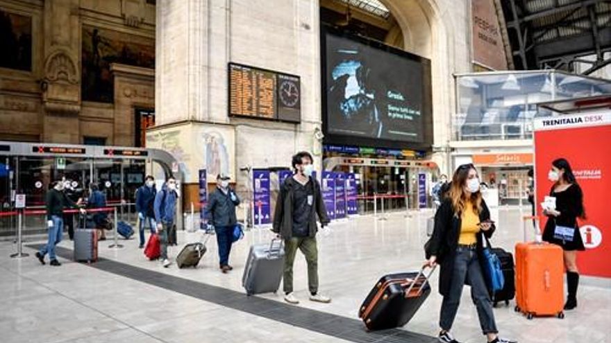 Estación de Milán con viajeros llevando mascarillas.