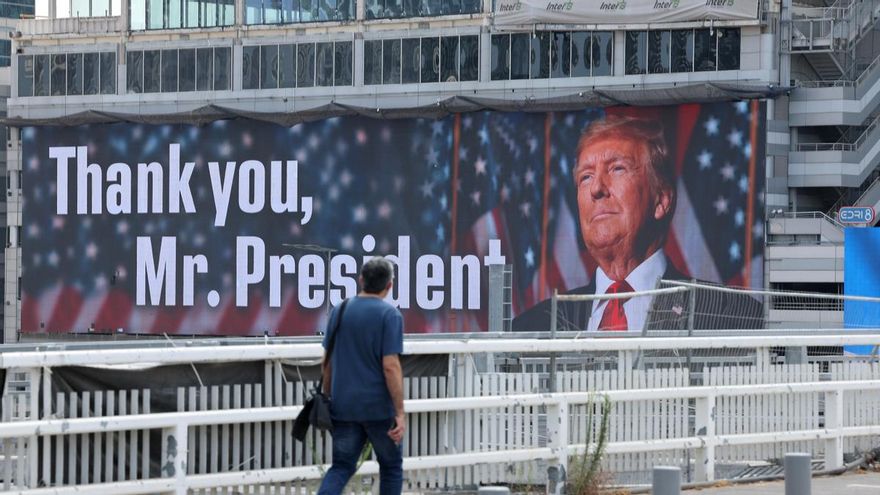 Un hombre pasa por el cartel para Donald Trump em Tel Aviv este domingo.
