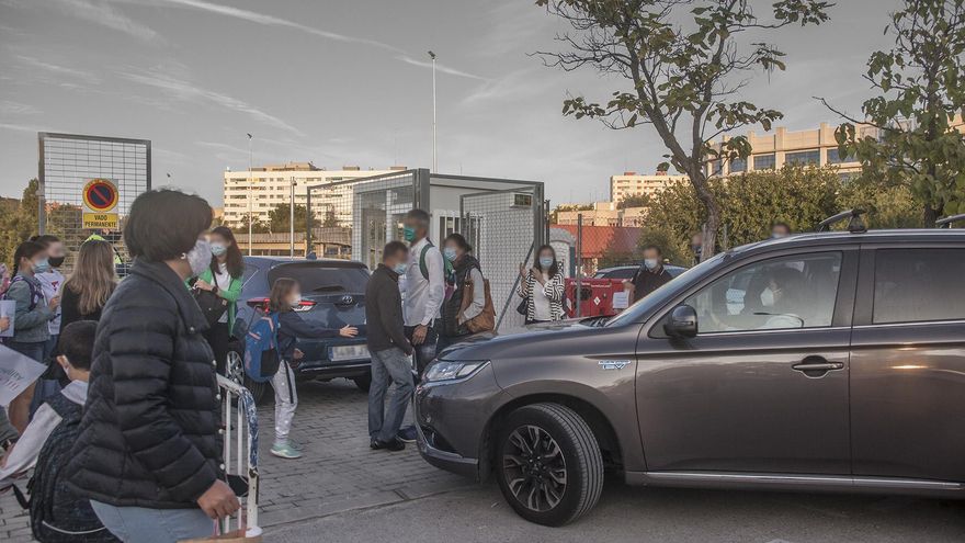 Entrada del colegio: niños con mochilas esquivando coches que van al parking.
