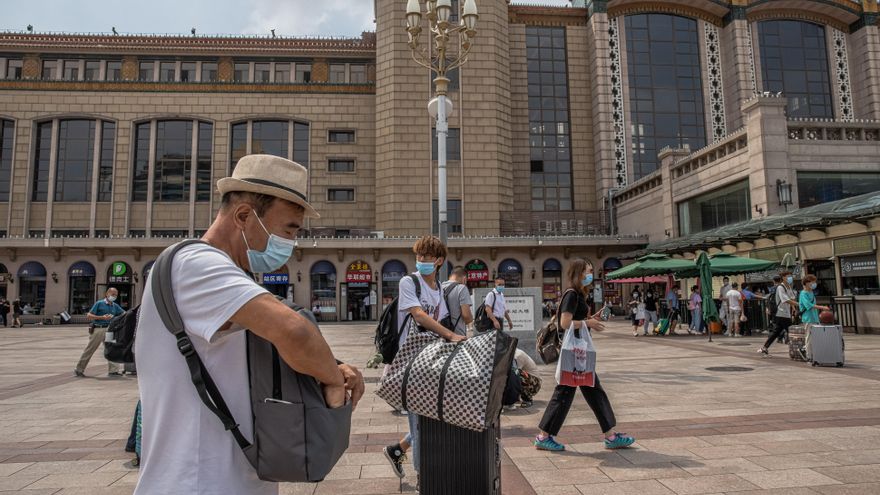 Viajeros protegidos con mascarillas se dirigen a la estación de tren de Pekín. EFE/EPA/ROMAN PILIPEY