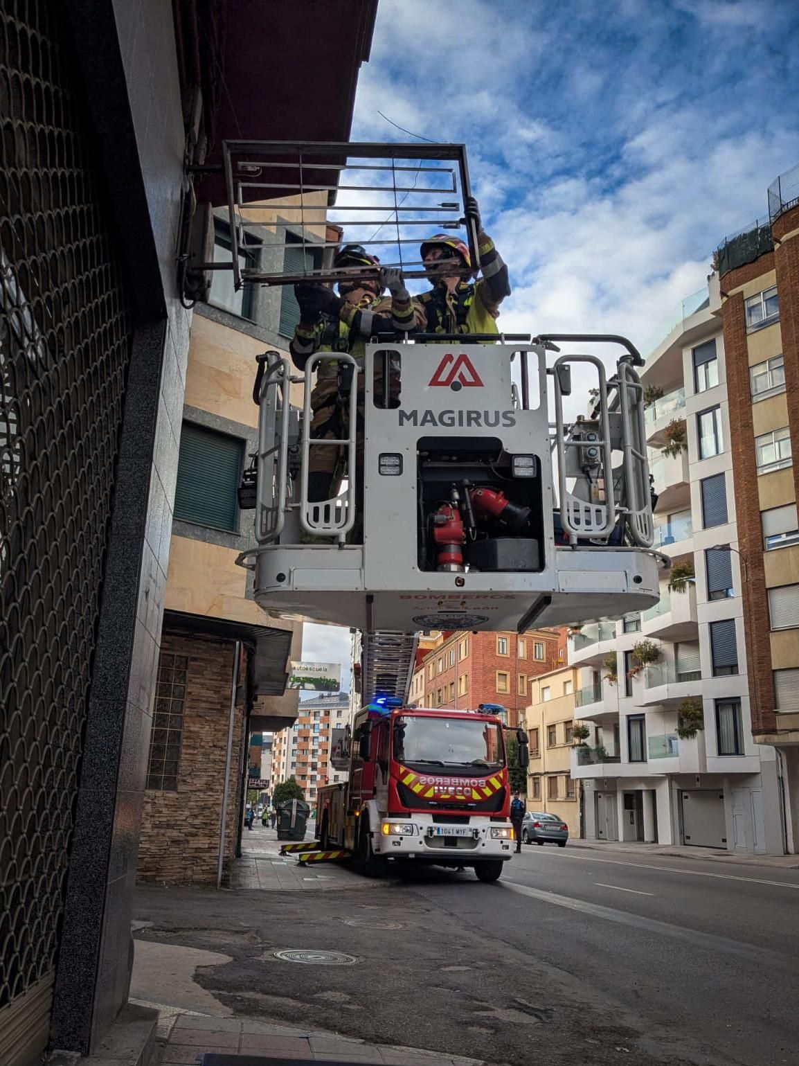 Los bomberos y su dotación de grúa retirando un elemento comercial peligroso de un local cerrado.