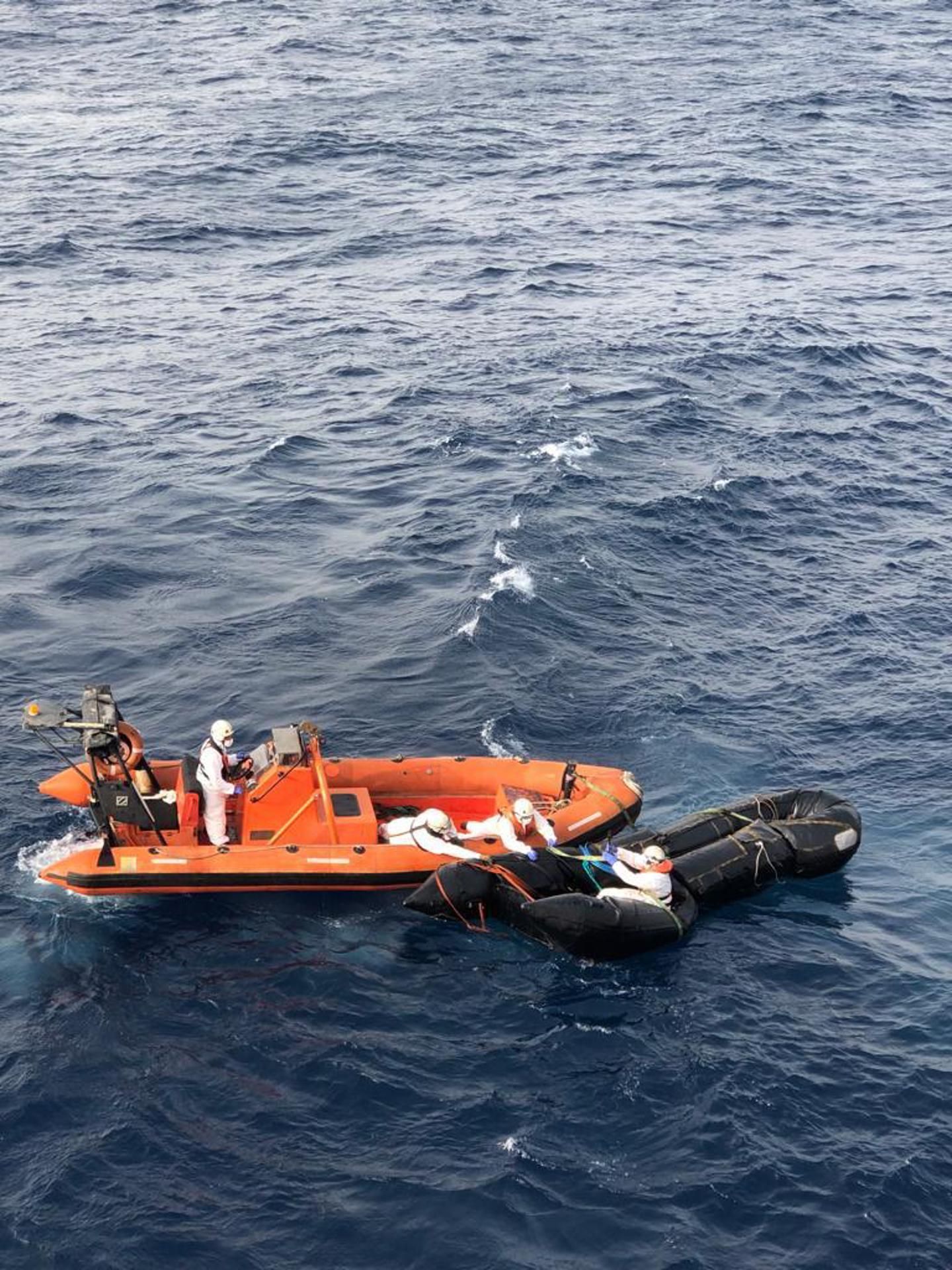 Los marineros del buque Miguel de Cervantes, de Salvamento Marítimo, aseguran el 2 de octubre desde una lancha auxiliar la neumática de la que fue rescatado la víspera en helicóptero el joven marfileño Fofana V., tras nueve días a la deriva