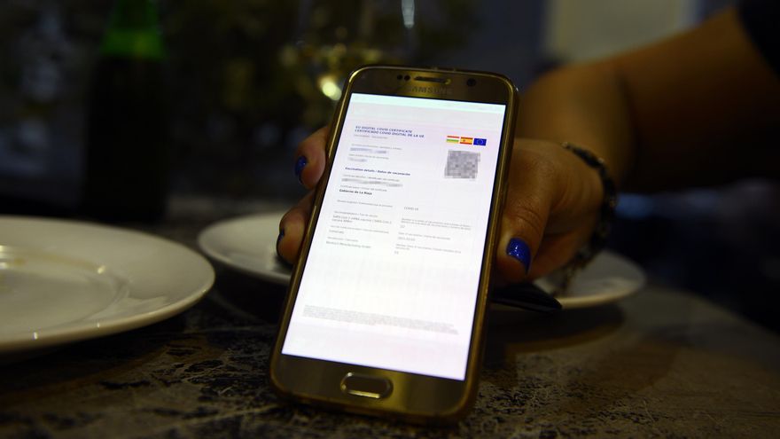 Una cliente exhibe su pasaporte COVID en una cafetería de Ourense.