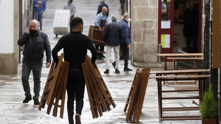Un camarero monta una terraza en una calle de Santiago de Compostela. Esta noche entran en vigor las nuevas medidas aprobadas por la Xunta, entre ellas, que las reuniones queden limitadas a un máximo de cinco personas. En Compostela los encuentros quedan limitados únicamente a convivientes. Los bares y cafeterías verán restringidos sus servicios en el interior de los locales, y las terrazas al 50%. EFE/Lavandeira jr