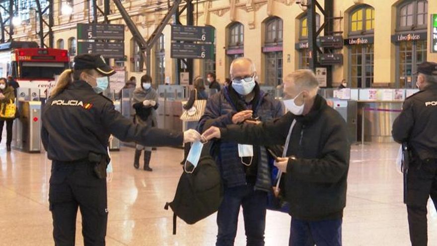 Agentes de la Policía reparten mascarillas en la estación del Norte de València.
