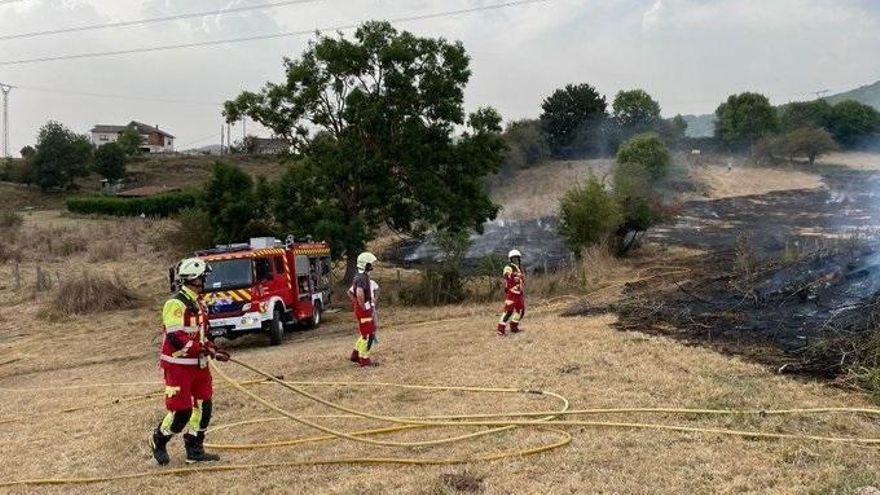 Bomberos extinguen un incendio en una pradería.