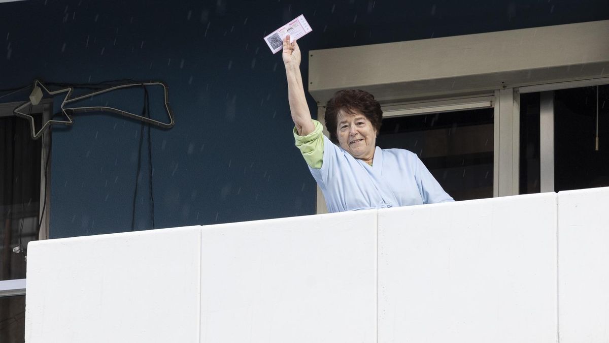 Una vecina del barrio de Mesa y López, donde se encuentra la administración, muestra desde su balcón una participación del número premiado. EFE/ Quique Curbelo