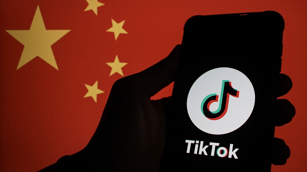 Un logo de TikTok en un móvil con una bandera china al fondo, en una imagen de archivo