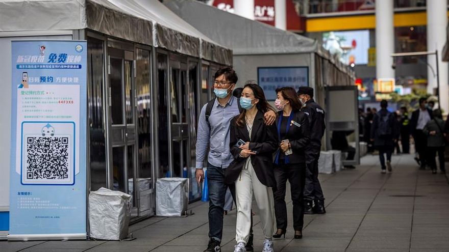 La gente pasa por una cabina de vacunación callejera para Covid-19 en una zona comercial principal en Shanghai, China