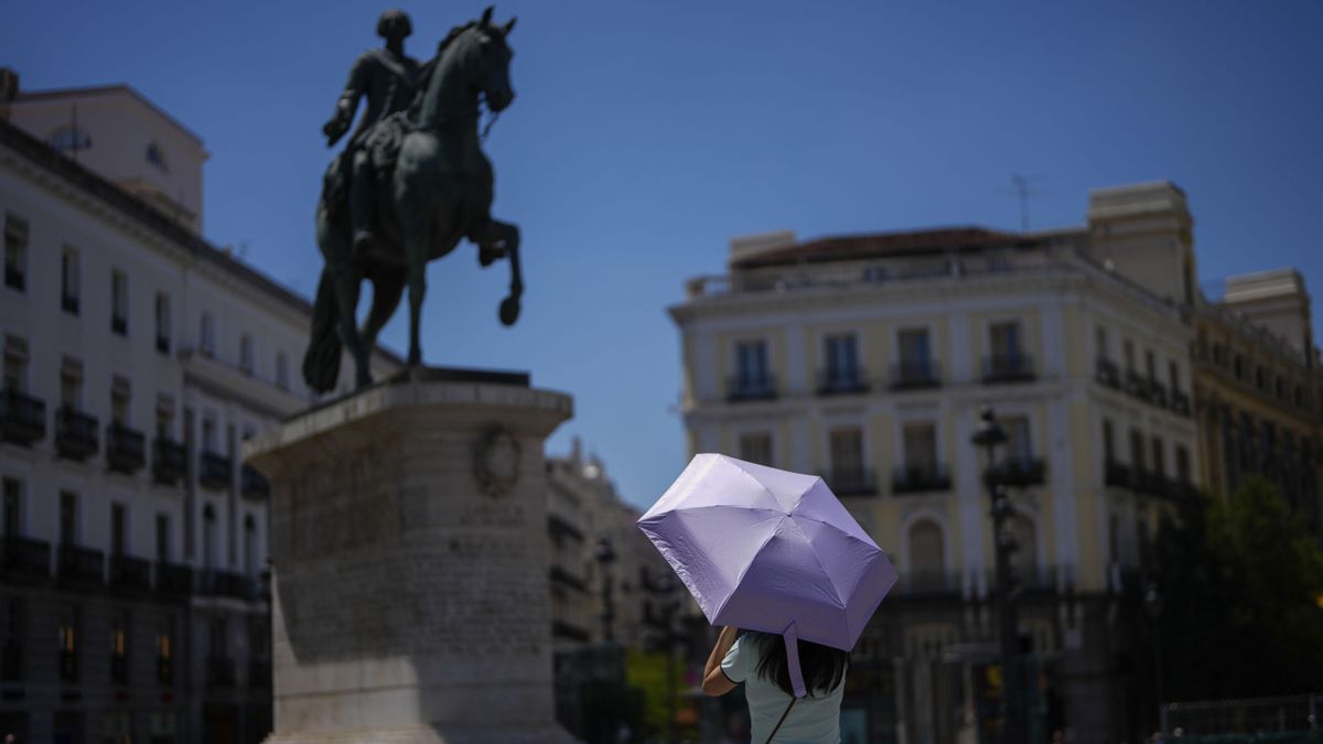 Una mujer se protege del calor con un paraguas en el centro de Madrid