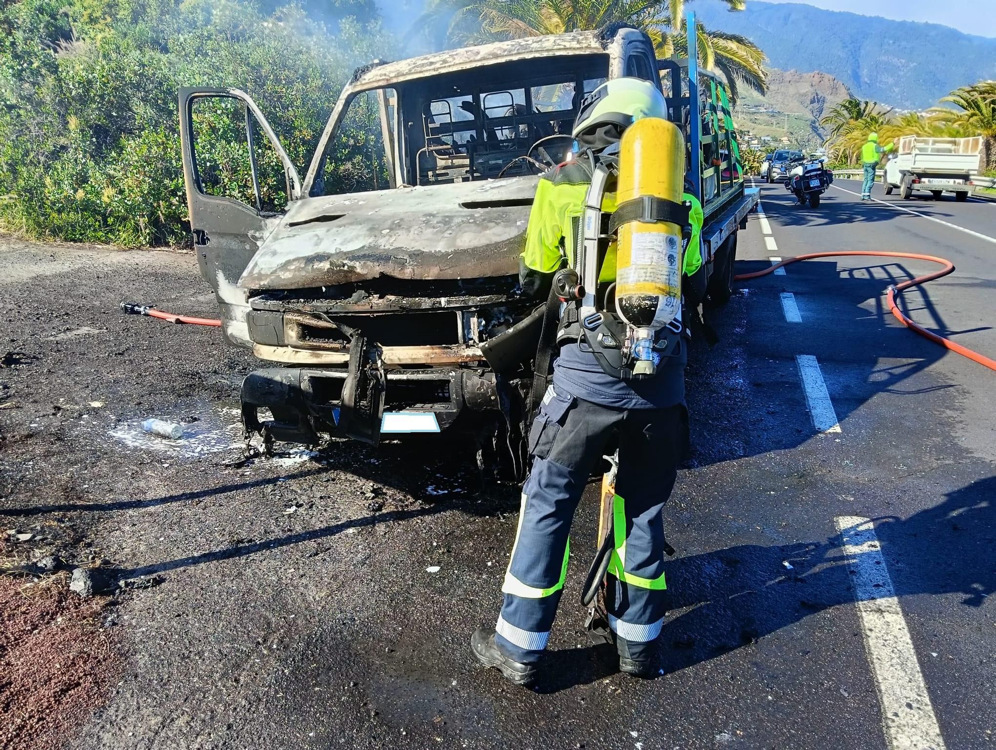 Un bombero durante las tareas de extinción del incendio de una camioneta en la carretera del aeropuerto de La Palma.