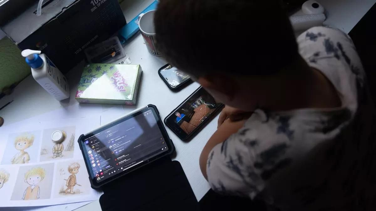 Un niño usando un teléfono móvil y una tablet.