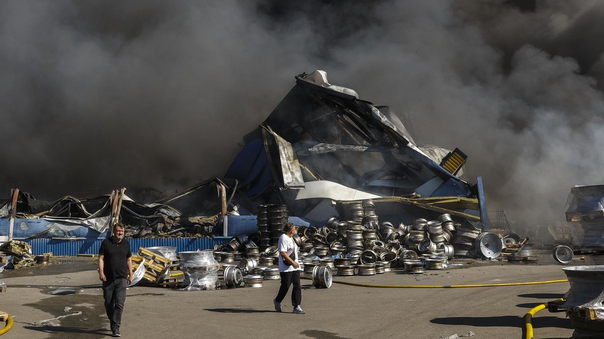 Dos personas caminan por el lugar de un ataque ruso contra un almacén de mercancías cerca de Kiev, Ucrania, este sábado.